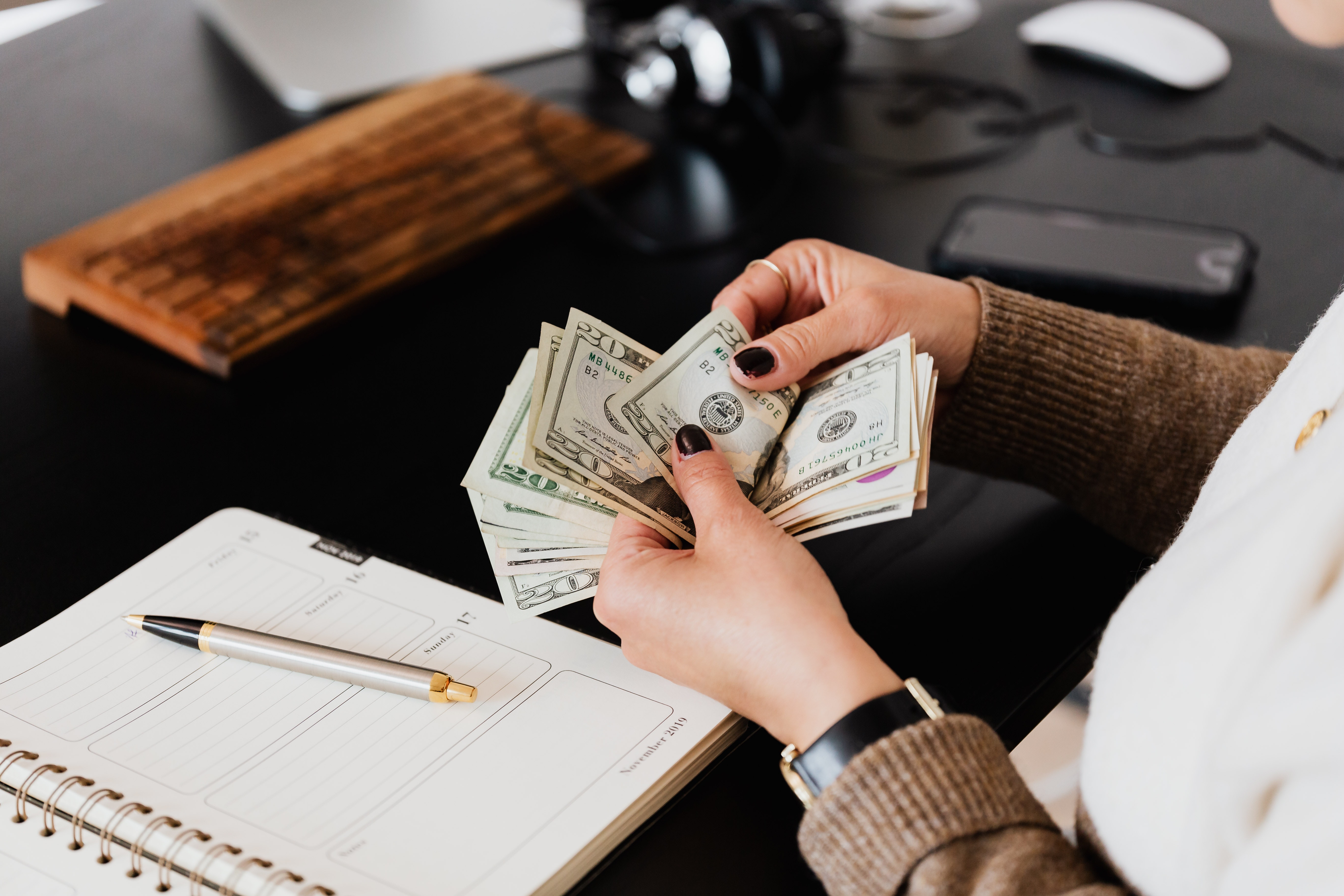 A person thumbs through a stack of bills over a desk.